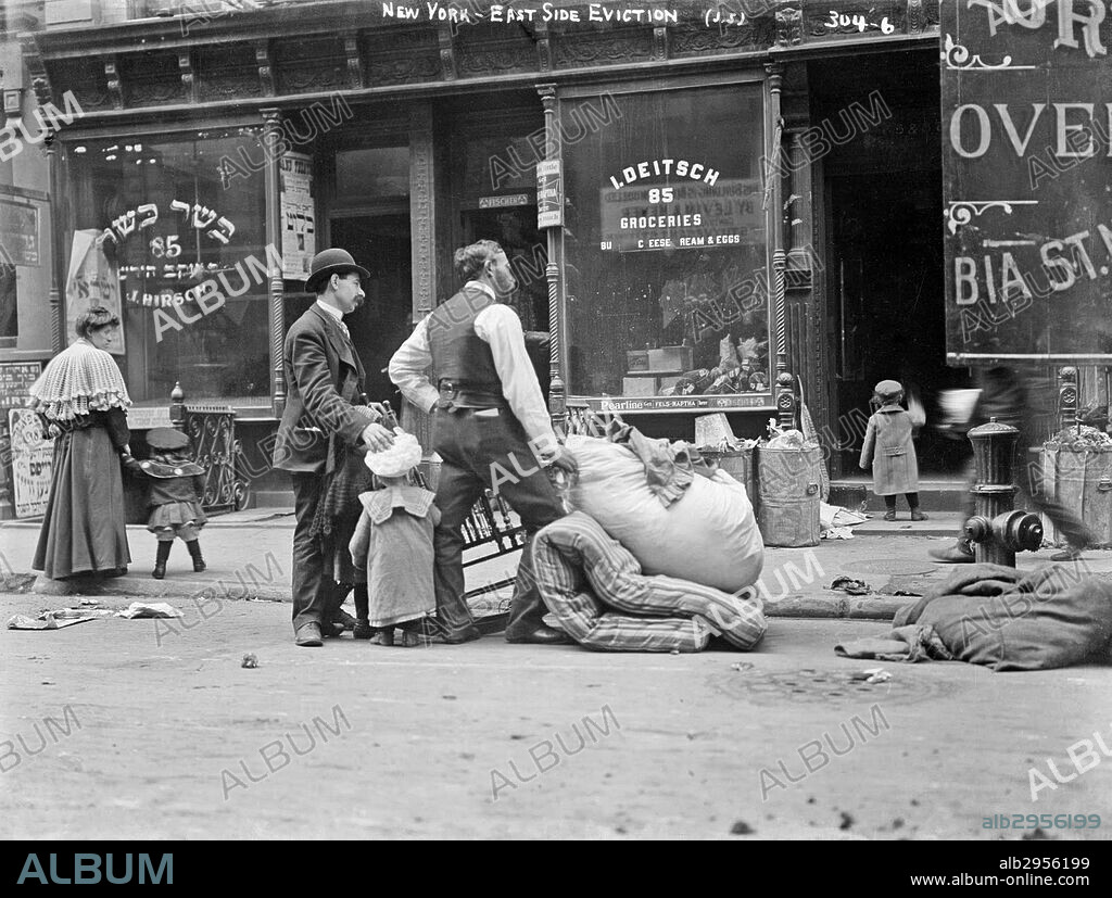 Photograph of the eviction of a poor Jewish family from their home in New York City. They stand outside of a Jewish grocery store. Dated 1910.