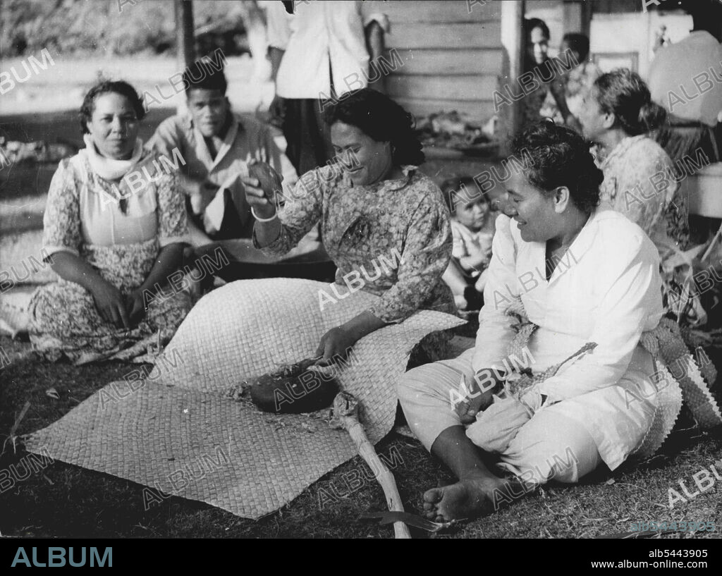 The Queen Will Visit Tonga -- Tongan woman making Kava. The national drink, made from the Dried Roots of plant belonging to the pepper family. In Tonga it is the woman who prepare the drink, unlike Fiji where the men are responsible. Section of the root are pounded between Two basalt stones. The fragments falling on the mat spread below. These are gathered together aid placed it the wooden bowl, visible under the girl's arm. H.M. The Queen and Duke of Edinburgh arrive at Tonga on December 19. Their second pacific halt. December 2, 1953. (Photo by Paul Popper).