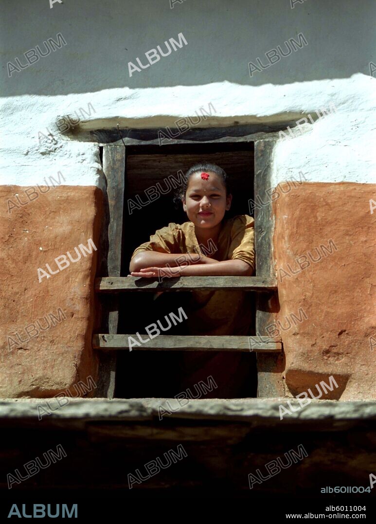 NEPAL Tatopani Village Girl framed by her wooden window.