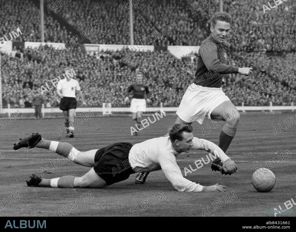STORBRITANNIEN LONDON 1959-10.. Orig. bildtext... SWEDEN WINS INTERNATIONAL AT WEMBLEY. Sweden this afternoon beats England by 3 goals to 2 in the World Cup Match. This picture shows T.E. Hopkinson, England's Goalkeeper, dives to clear a shot by A. Simonsson, Sweden's brilliant centreforward. Orig. bldtext... LANDSKAMPEN SVERIGE - ENGLAND: Engelske målvakten Hopkinson dyker framför fötterna på Simonsson. Orig. bildtext... BOLTON GOALIE HOPKINSON A LIKELY CHOICE FOR CHILE. För komplett text se orig. Anm. Agne Simonsson fick bragdguldet 1959 För fullständig text se original Matchbilder VM i fotboll persons: AGNE SIMONSSON;EDDIE HOPKINSON sites: SVERIGE*;STORBRITANNIEN;LONDON.