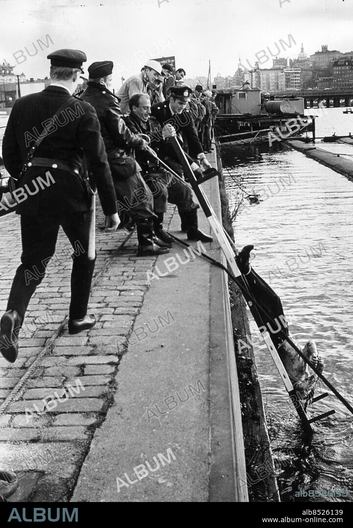 STOCKHOLM 19661111 - Träskmorden i Stockholm. Vägarbetaren Nils-Erik Stenbäck, det tredje offret för gärningsmannen Hans Marmbo, bärgas vid Riddarholmskajen. De övriga två offren dumpades på andra platser i Stockholm. Namnet "Träskmorden" kommer från de skumraskkvarter runt Brunnsgatan där morden utfördes. . Foto: Arne Schweitz Kod: 1049 . COPYRIGHT SCANPIX SWEDEN.