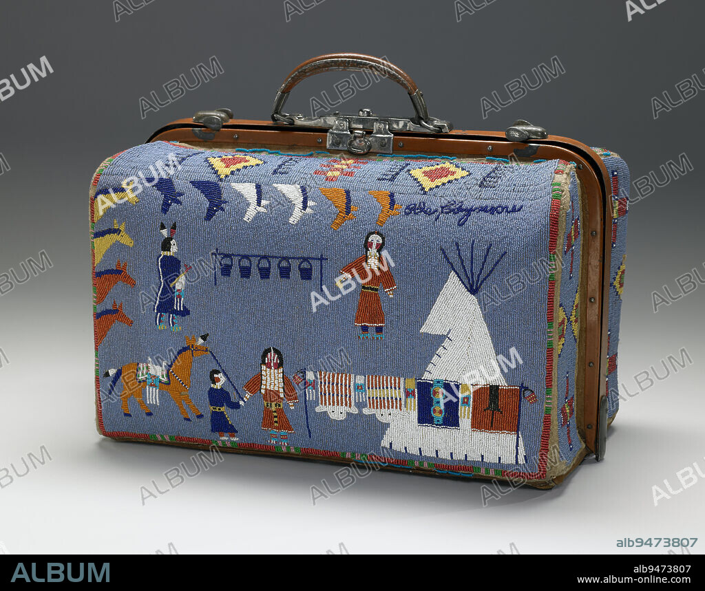 Suitcase, 1880-1910, Nellie Two Bear Gates, Iháktuwana Dakhóta, Standing Rock Reservation, born 1854, 12 1/2 x 17 11/16 x 10 1/4 in. (31.75 x 44.93 x 26.04 cm) (closed), Beads, hide, metal, oilcloth, thread, United States, 19th-20th century, Nellie Gates made this beaded suitcase on the occasion of her relative Ida Claymores marriageClaymores name appears in the upper right corner. A gift, the suitcase illustrates the union of two families. One side depicts the bride and her family among the food and gifts offered to celebrate the marriage. At top, eleven horses frame two figures (likely Idas parents), who stand on either side of suspended kettles symbolizing the large amounts of food given at this time. At bottom, the bride stands next to her tipi, fully adorned, with more gifts: (left to right) beaded pipe bags; two full, beaded buffalo robes; a trade cloth with beaded blanket strip; and a robe with an animal figure. The other side likely relates to the grooms family, who were ranchers. Two cowboys, possibly relatives, rope cattle, illustrating the grooms familys wealth and his ability to provide for the bride. Gates captures movement in this static medium by showing the ponys tail flying in the wind and a cowboy throwing his lasso.