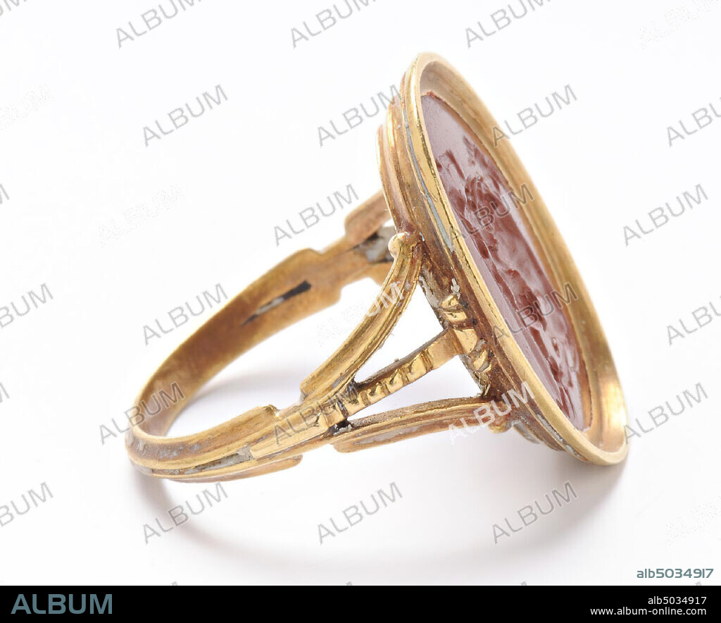 Vz: a lion sits on a goat, holds the animal with two legs in its grip and bites it in the neck, the goat, which has its legs under its body, has two big horns and a beard, the head The goat is still upright., gem, intaglio, ringstone, jasper, Color: red, Shape: oval, Machined: in modern gold ring, Method: modeling with large rounded drills, detailing with short rounded wheel grooves., 15 x 12 mm, D. 3 mm, Roman imperial age?.