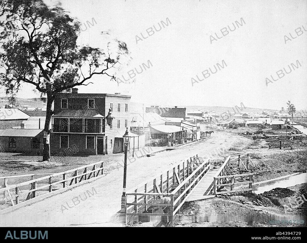 Negative - Bendigo, Victoria, 1857, Bridge Street, Sandhurst with the Bendigo Hotel in the background. There is a bridge over Bendigo (?) Creek in the foreground and a lantern on the bridge.