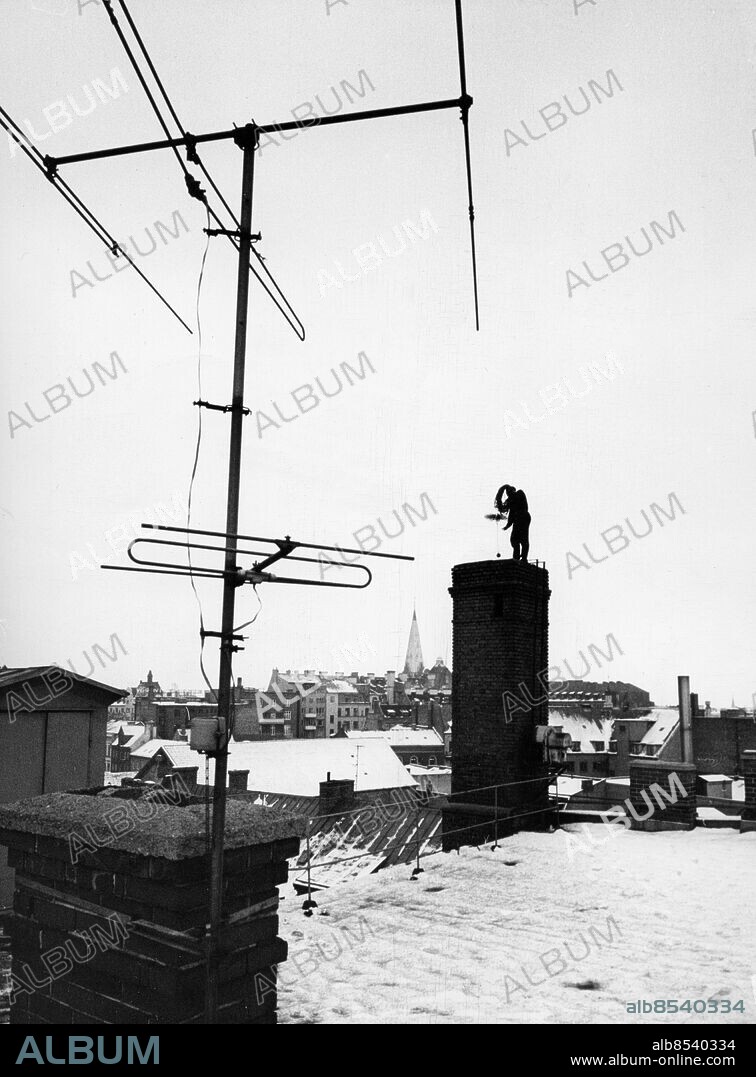 Sotare på skorsten på hustak i Malmö 1969. S:t Petri kyrka i bakgrunden TV-antenn antenn. Foto: Foto: Rolf Ziegler / Sydsvenskan / IBL Bildbyrå *** Local Caption *** A Chimney sweep, Malmoe, Sweden , 1969.