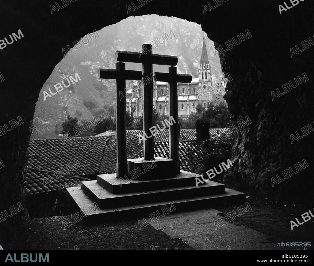 CALVARIO DE TRES DE CRUCES DE PIEDRA EN EL TUNEL DE ACCESO A LA CUEVA DE CON LA BASILICA DE SANTA MARIA LA REAL AL FONDO.