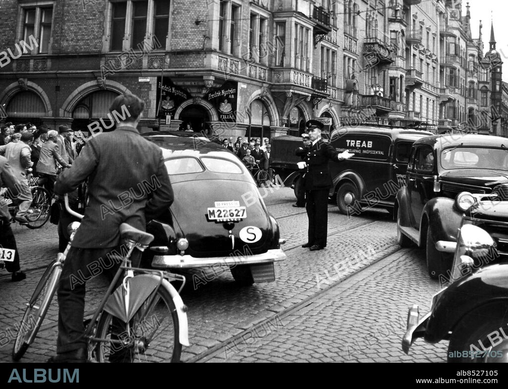 Orig.bildtext... SCOTLAND YARD-MAN DIRIGERAR MALMÖTRAFIKEN. Scotland Yards främste trafikexpert, Chief Inspector Leonard Weir, gästar f.n. Malmö i anledning av trafikveckan här. På torsdagseftermiddagen, vid tidpunkten då Kockums varv slutar, fick han tillfälle att dirigera trafiken i Malmös svåraste korsning, Regementsgatan-Morescobron. Här har trafiken stannat av ett ögonblick, men mr Weir och en svensk trafikpolis klarade snart upp det hela. persons: Leonard Weir sites: MALMÖ ;SVERIGE ;STORBRITANNIEN*.