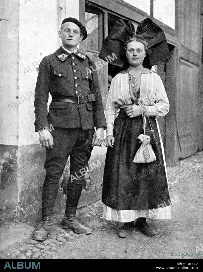 Couple in traditional dress, Alsace-Lorraine, Rhine, 1936. Alsace-Lorraine has been part of both Germany and France. From Peoples of the World in Pictures, edited by Harold Wheeler, published by Odhams Press Ltd (London, 1936).