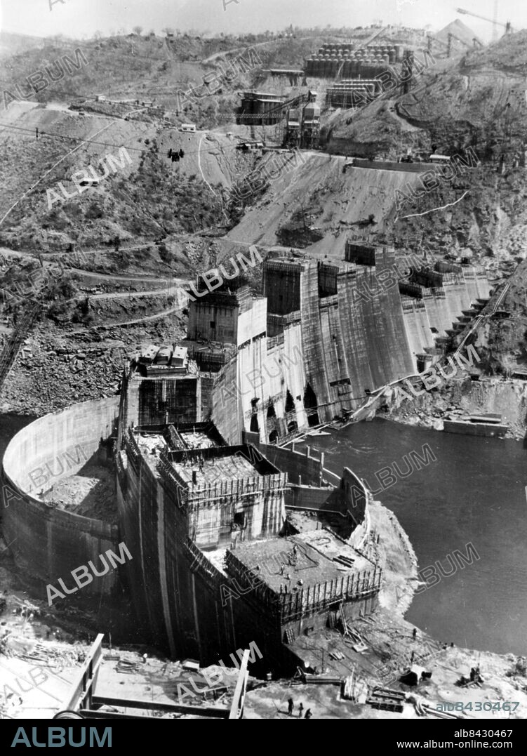 Orig. bildtext... KARIBA DAM NEARS COMPLETION. After the nearly disasterous floods of last March, the Dam across the Zambezi River at Kariba, Rhodesia, South Africa is now taking final shape. The dam, due to be comissioned in January 1960, will be 420ft high, 1900ft long, and wide enough to take a 40ft roadway. It will create a reservoir on the Zambezi River 175 miles long, covering about 2,000 square miles. Anm. Kraftverk i Zambesifloden på gränsen mellan Zambia (f d Nordrhodesia) och Zimbabve (f d Sydrhodesia, Rhodesia) Dammar Flygfoto sites: AFRIKA ;RHODESIA ;ZAMBIA ;ZIMBABVE.