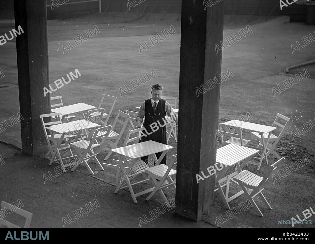 Göteborg - 1943-03-10 - I vårsolen tar Giovanni Galligani fram utemöbler och sätter dem mot vägen bakom huvudläktaren -. Denne man svarade för förplägnaden på Gamla Ullevi i många år - *** Local Caption *** GT Låda 1943-mars-april-maj-jun-jul-aug-. KAMERAREPORTAGE.