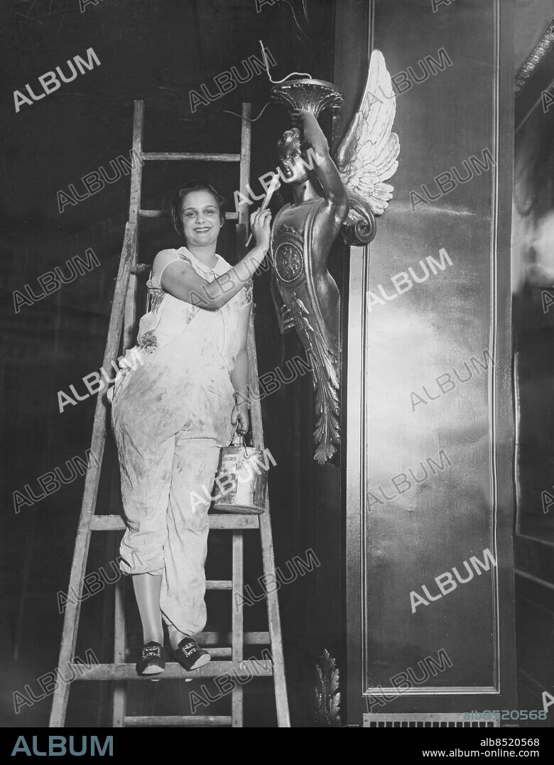Orig. bildtext... GLORIA GOULD READY TO OPEN NEW MOVIE THEATRE. Mrs. Gloria Gould Bishop, youngest daughter of the late George Jay Gould and his first wife, whose activities since her debut two years ago have included solo dances, instruction in dancing and writing for magazines, has now undertaken management of a Broadway motion picture house, the Embassy, now nearing completion. It will open soon and according to plans of Miss Gould all of the officials and employees of the theatre will be women. Miss Gould may give a solo dance or have her dancing pupils perform at the theatre. Photo taken today shows Miss Gould putting finishing touches to decoractions in the new Embassy Theatre of which she will have entire management. Anm. Stegar Lampetter Biografägare Arbetskläder Änglar persons: GLORIA GOULD BISHOP sites: NEW YORK;USA.