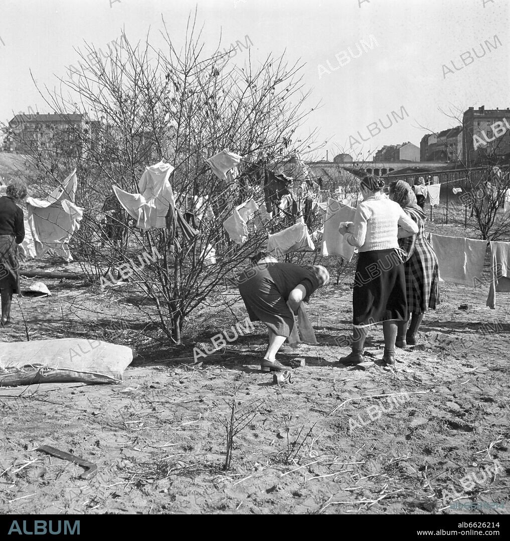 A factory hall on Oderstraße at Tempelhof airport in Berlin-Neukölln serves as a refugee camp for former GDR citizens, in 1953. Women are drying their laundry on 11 March 1953 on an open space in the fenced camp. 11/03/1953