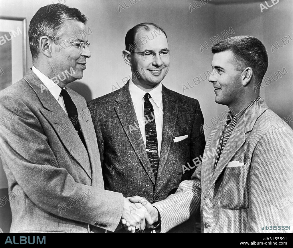 United States:  c. 1958. A young man is greeted by an older man in a suit.
