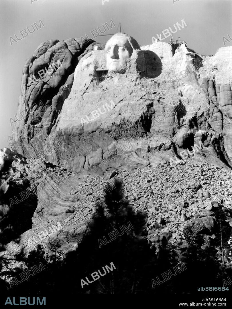 The first attempt at Thomas Jefferson on Mount Rushmore. Jefferson's head was started in 1934, to the right of Washington. Before the head was complete, Borglum requested that it should be blasted off due to poor rock quality. Jefferson's head was restarted on Washington's left. Mount Rushmore National Memorial is a sculpture carved into the granite face of Mount Rushmore near Keystone, South Dakota. Sculpted by Danish-American Gutzon Borglum and his son, Lincoln Borglum, Mount Rushmore features 60 foot sculptures of the heads of four United States presidents: George Washington, Thomas Jefferson, Theodore Roosevelt, and Abraham Lincoln. Construction on the memorial began in 1927, and the presidents' faces were completed between 1934 and 1939. Although the initial concept called for each president to be depicted from head to waist, lack of funding forced construction to end in late October 1941. Mount Rushmore has become an iconic symbol of the United States, and attracts over three million people annually. Photographed by Charles D'Emery, undated.