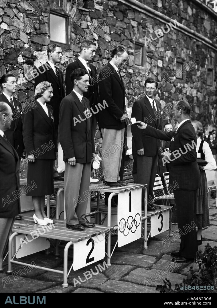 HELSINGFORS 19520729 . Prins Axel av Danmark delar ut guldmedaljen till Britton Chance från USA. USA segrade i seglingens 5,5-metersklass vid de olympiska spelen i Helsingfors, tvåa blev Norge och trea Sverige med båten Hojwa. Folke Wassén i det svenska laget ses längst till höger på prispallen.. Foto: Kamerareportage / TT / Kod: 224.