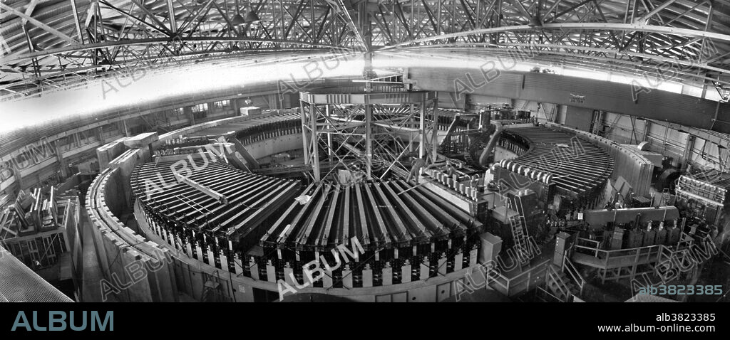 Panoramic view of interior of Bevatron, 1956. The Bevatron was a particle accelerator (specifically, a weak-focusing proton synchrotron) at Lawrence Berkeley National Laboratory, which began operating in 1954. At the time the Bevatron was designed, it was strongly suspected but not known, that each particle had a corresponding anti-particle of opposite charge, identical in all other respects, a property known as charge symmetry. The Bevatron was built to be energetic enough to create antiprotons, and thus test the hypothesis that every particle has a corresponding anti-particle. Confirmation of the charge symmetry conjecture in 1955 led to the Nobel Prize for physics being awarded to Emilio SegrÃ¨ and Owen Chamberlain in 1959. Hundreds of new particles and excited states were suddenly revealed, which marked the beginning of a new era in elementary particle physics. Luis Alvarez inspired and directed much of this work, for which he received the Nobel Prize in physics in 1968. The Bevatron received a new lease on life in 1971, when it was joined to the SuperHILAC linear accelerator as an injector for heavy ions. The next generation of accelerators used "strong focusing", and required much smaller apertures, and thus much cheaper magnets. The Bevatron was finally decommissioned in 1993. The demolition of the Bevatron began in 2009 and completed in 2011.