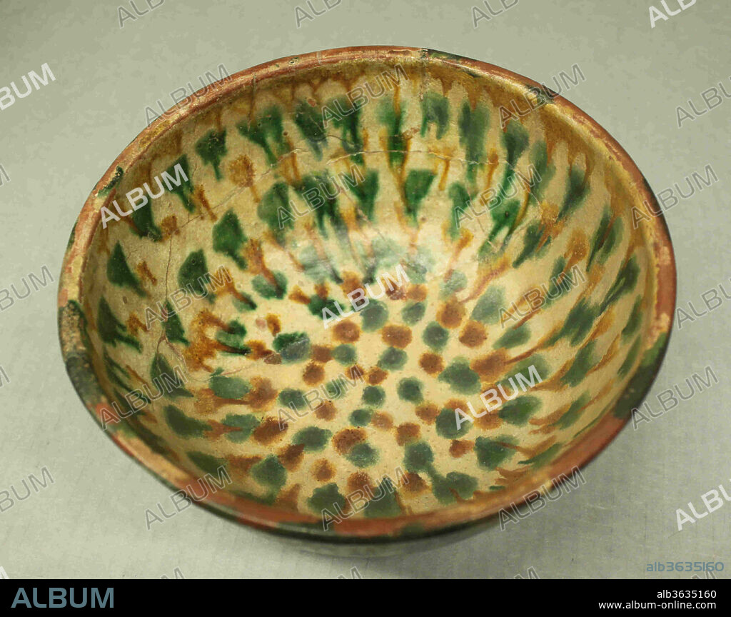 Six Vessels with Splashed and Incised Decoration (Sgraffito Ware). Dimensions: H. 1 9/16 in. (4 cm)
Diam.  3 1/8 in. (8 cm). Date: 10th century.
Two techniques of decoration were used on this bowl excavated from Nishapur in eastern Iran. In a technique known as sgraffito, a festoon and leaf-like motifs were etched into a white slip that had been applied to the earthenware body and allowed to dry. The etching reveals the body of the bowl, in this case an earthy red fabric, which then stands out in contrast to the white slip to showcase the motif. Next, blobs of green, brown and yellow glazes were applied to the surface with a thin coating of transparent glaze. When the bowl was fired, these colored glazes were allowed to run down the sides of the bowl in the kiln, producing dramatic streaks on the steep exterior sides of the bowl. The combination of the sgraffito and splashing techniques was very popular in the medieval Islamic lands and examples have been attributed to production centers in Syria, Iraq, and Iran.
