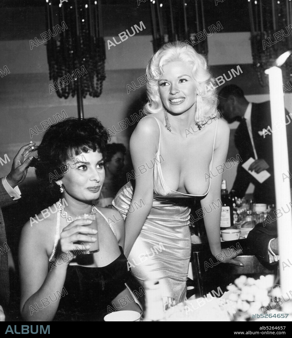 JAYNE MANSFIELD et SOPHIA LOREN. American actress and model Jayne Mansfield, known for her publicity stunts, attended a dinner at the exclusive Beverly Hills Romanoff's restaurant hosted by Paramount Pictures to officially welcome Italian actress Sophia Loren to Hollywood. A photograph of the two women, with Loren casting a sideways glance at Mansfield's cleavage, was distributed world-wide and became an international sensation.