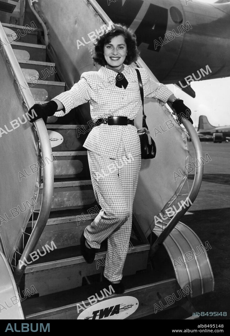 Orig. bildtext... VIVECA LINDFORS, AMERICA'S NEWEST SWEDISH STAR, arrived in Los Angeles yesterday (27) from Paris with the long and short of the skirt question in the European fashion center. In the smart shops, she said, as she emerged from a Trans-World Airways' plane at Municipal Airport in Inglewood, the skirts are very long indeed. Miss Lindfors' word may be accepted as authority on this since scenes of her engaged in window-shopping with Dennis Morgan were filmed in Paris for To the Victor. As for Viveca, she maintained complete neutrality in the long-versus-short battle - she wore slacks. Miss Lindfors was first to arrive of the Warner Bros.' company, headed by director Delmer Daves, which has spent the past six weeks in Paris and Normandy filming scenes for the post-war drama. She was accompanied by Ann Marie Joel, who will act as technical advisor on additional scenes to be filmed at the Burbank studio. In the Daves - Morgan party, which arrived later in the day due to soace shortage, were Victor Frances, who was signed in Paris for the top supporting role in the film, and cameraman Robert Burks. Orig. bildtext... VIVECA LINDFORS HAR ÅTERVÄNT TILL USA efter sommarens filmning i Paris. Orig. bildtext... VIVECA ÅTER I USA. Viveca Lindfors har återkommit till USA efter filmningen i Paris och ses här i chic långbyxklädsel, då hon debarkerade planet i Inglewood, Los Angeles. 9-47 Anm. V Lindfors, 1920-1995, svensk skådespelare. Ankomster Byxdressar Filmstjärnor Resenärer persons: VIVECA LINDFORS sites: LOS ANGELES;USA;SVERIGE*.