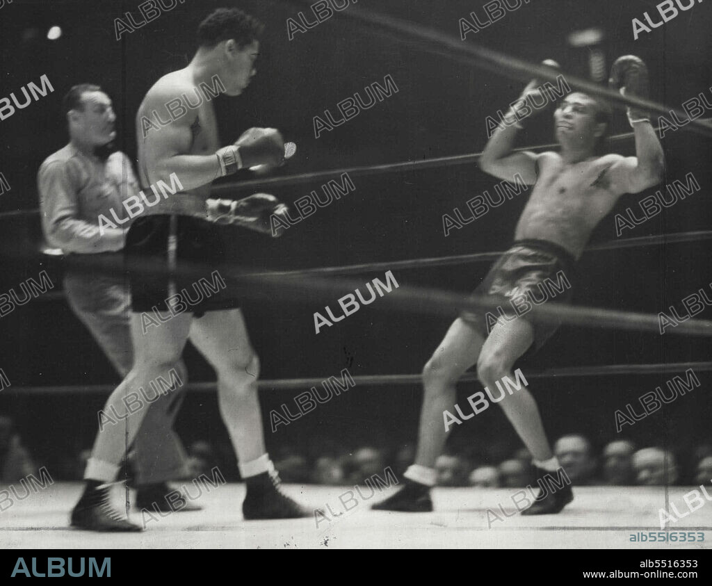Lewis Surrenders -- Dazed and reeling under a barrage by Champion Joe Louis, John Henry Lewis the challenger is shown as he tossed his hands in the air in an unconscious gesture of surrender near the end of the one round battle at Madison Square Garden, New York, Jan 25. January 27, 1939. (Photo by Associated Press Photo).