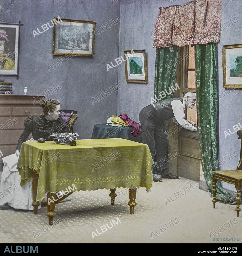 Magic Lantern slide circa 1900 hand coloured. Victorian/Edwardian era. Life models.Slide 4 of The fireman's wedding (recitation: Bamforth & Co., 21 slides, 1902). A man looking out of an open window with his wife sitting at the table.