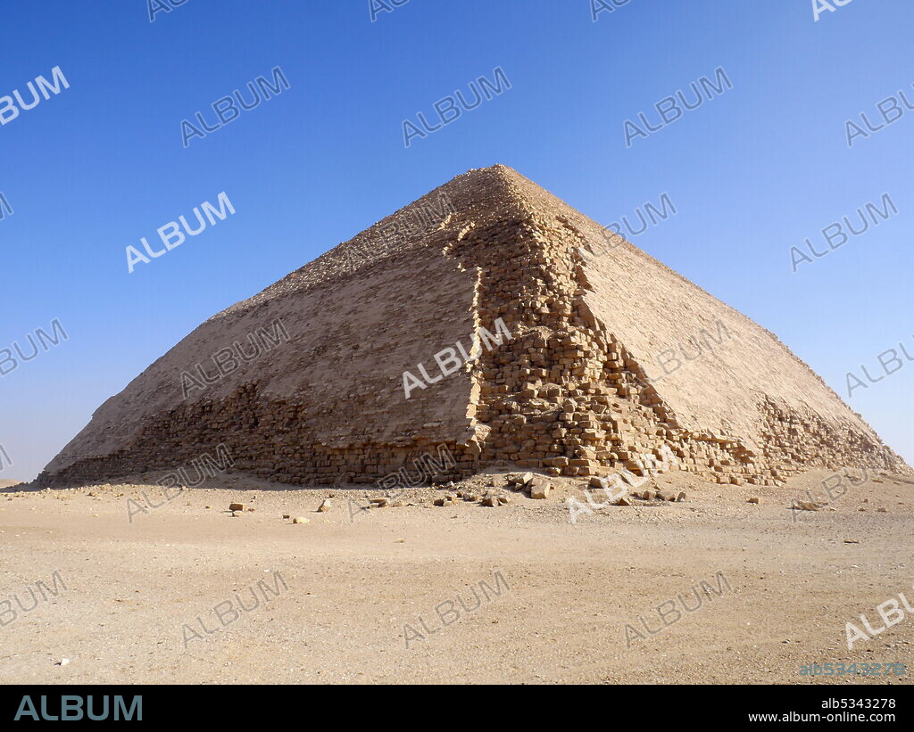 The Bent Pyramid is an ancient Egyptian pyramid located at the royal necropolis of Dahshur, approximately 40 kilometres south of Cairo, built under the Old Kingdom Pharaoh Sneferu (c. 2600 BC). A unique example of early pyramid development in Egypt, this was the second pyramid built by Sneferu. The Bent Pyramid rises from the desert at a 54-degree inclination, but the top section (above 47 meters) is built at the shallower angle of 43 degrees, lending the pyramid its very obvious 'bent' appearance..