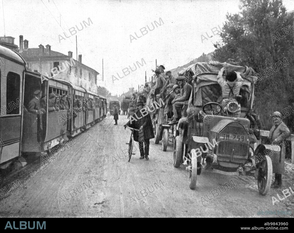 'French Troops in Italy; Two convoys on the road from Brescia to Verona: on the left, an electric train loaded with Italian troops; on the right, road-trucks transporting French troops', 1917. From "L'Album de la Guerre 1914-1919, Volume 2" [L'Illustration, Paris, 1924].