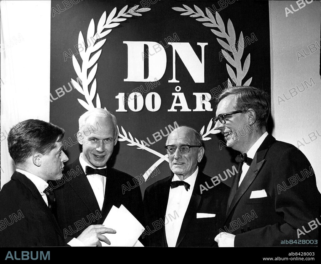 Stockholm 1965-01-07. Framför DN:s hundraårsemblem ses redaktionschef Börje Dahlqvist, chefredaktör Olof Lagercrantz, faktor Herman Lönn som anställdes på1800-talet och chefredaktör Sven-Erik Larsson. Foto: Sven Åsberg / SvD / TT / kod 12014.