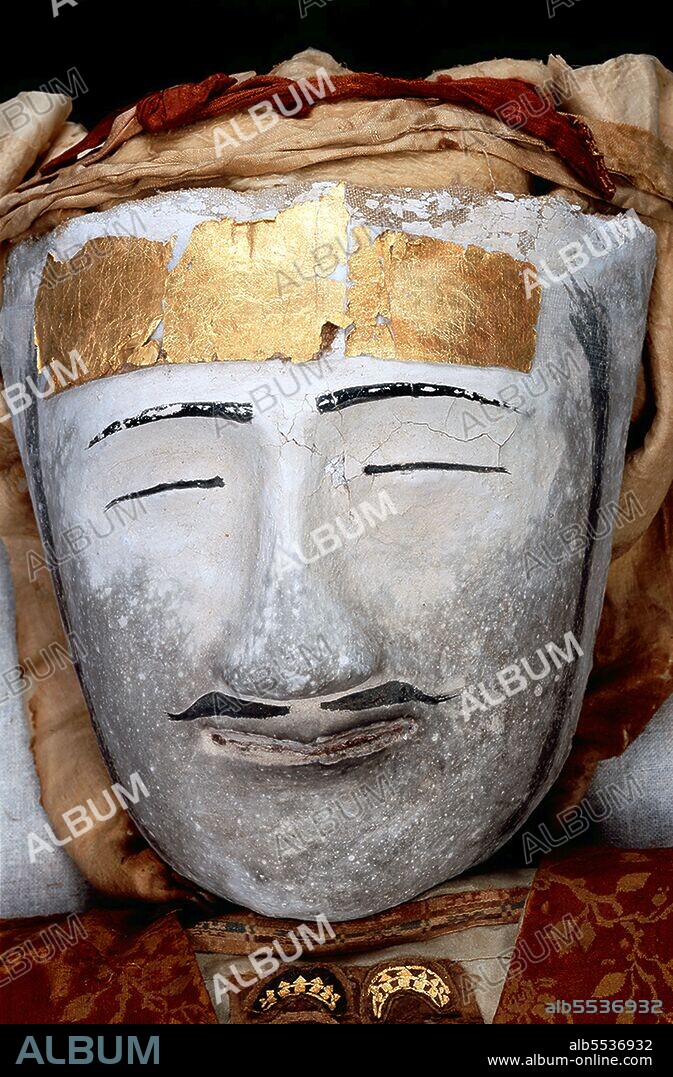 The best preserved of the corpses discovered at the cemetery at Zaghunluq in the Tarim Basin, is the 'Yingpan Man'. The two metres tall, 2,000 year old Caucasian mummy was discovered in 1995. His face was blond and bearded and was covered with a gold foil death mask; he also wore an elaborate golden embroidered red and maroon wool garments with images of fighting. His head rests on a pillow in the shape of a crowing cockerel. The Zaghunluq cemetery contained 29 mummies, dating from 1800-500 BCE.