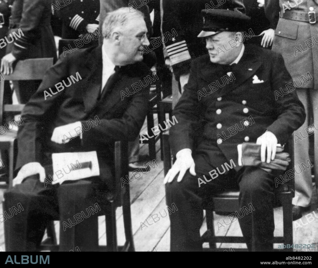 Orig. bildtext... MYSTERY SOLVED Aboard H.M.S Prince of Wales, at sea, The mysterious cruise of president Roosevelt has finally been explained by the world-haking news that he has met with Britain’s Prime Minister somewhere at sea. Here the two major figures chat, prayer books in their laps, shortly after sunday morning church services aboard the British man-of-war August 10th. At one such conference they formulated the eight-points-for peace text. Anm. F.D. Roosevelt, 1882-1945, USA:s president åren 1933-1945. W Churchill, 1874-1965. Han var brittisk premiärminister 1940-1945 och 1951-1955 Båtdäck Profiler Handskar Sitter Stolar Samtal pincené Jämförelser Flugor Kaptensmössor CD455 persons: FRANKLIN D. ROOSEVELT;WINSTON CHURCHILL sites: STORBRITANNIEN*;USA*.
