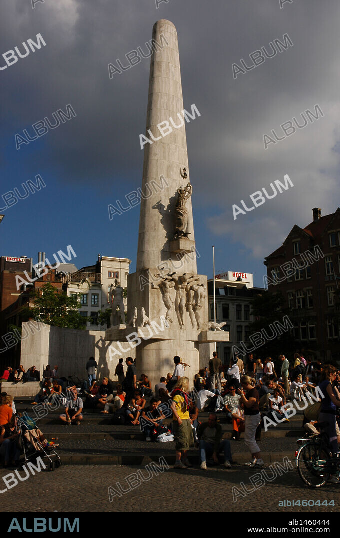 Gente sentada en la PLAZA DAM, a los pies del MONUMENTO NACIONAL, obelisco erigido en 1956 por el arquiecto holandés J. J. P. Oud y el escultor John Raedecker, en homenaje a los soldados caídos en la Segunda Guerra Mundial. Amsterdam. Holanda.