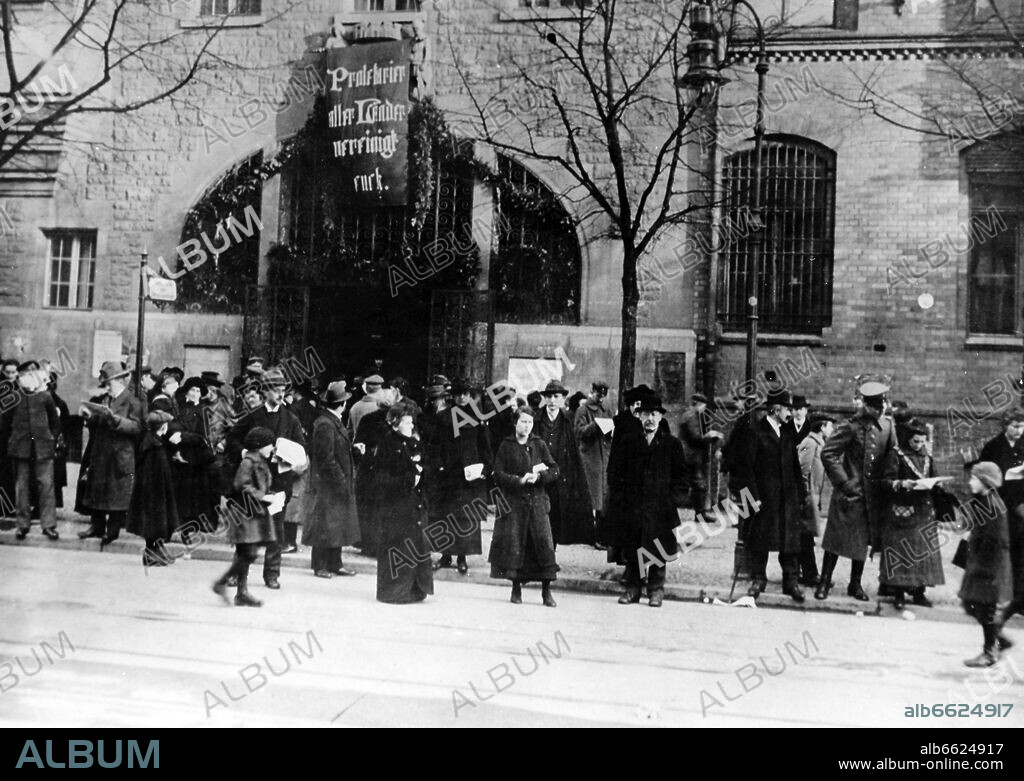German Revolution 1918/1919: Street scene in Berlin during the riots in late 1918/ early 1919 - Passers-by read the special edition of the newspapers / flyers in front of a building, on which the communist slogan "Proletarians of all countries, unite!" is attached. Photo: Fotoarchiv für Zeitgeschichte/Archiv. 1919
