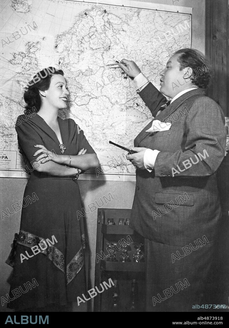 GERMANY BERLIN 1943-01-28 Orig. caption ... A FAMOUS GERMAN FILM ARTIST COUPLE IN HIS BERLIN HOME. Heli Finkenzeller and Will Dohm - both prominent names in German film - have already won many hearts abroad in large and small roles. Picture 2: Heli and Will discuss with full anticipation at next Wehrmacht tour. Photo: Photo UFA / AB Text & Bilder / SVT / Code: 5600 Folder: Finkenzeller, Heli H Finkenzeller, 1911-1991, German actor W Dohm, 1897-1948, German actor Photo series Photo report Planning for a tour with the German Armed Forces persons: WILL DOHM; HELI FINKENZELLER sites: GERMANY; BERLIN.