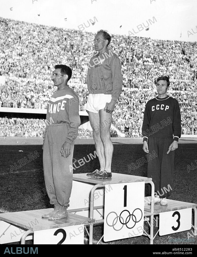 FINLAND HELSINGFORS 1952-07-20.. Tre löpare på prispallen efter finalen på 10000 m. vid de olympiska sommarspelen 1952. Från vänster ses Alain Mimoun (Frankrike), silvermedaljör, Emil Zátopek (Tjeckoslovakien), guldmedaljör, och Aleksandr Anufrijev (Sovjetunionen), bronsmedaljör.. Foto: DPA / AB Text & Bilder / SVT / Kod: 5600. Mapp: 10000 m. (O.S. -52) I:286H. Prisutdelningar Vinnare Segrare Trio Prispallar.