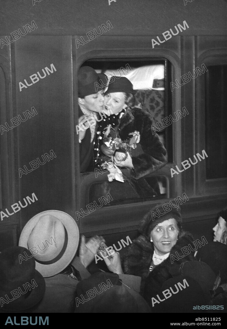 STOCKHOLM 1930-tal.. Orig. bildtext... TUTTA ROLF AVRESTE I FÖRRA VECKAN VIA BREMERHAFEN TILL HOLLYWOOD I SÄLLSKAP MED SIN PRIVATSEKRETERARE EVA TISELL. Tutta Rolf och Hans Ekman ta ett ömt farväl vid tågets avgång från Centralstationen. Orig. bildtext... TUTTA ROLF RESER TILL HOLLYWOOD. På onsdagskvällen avreste Tutta Rolf från Stockholm för att via Bremerhafen bege sig till Hollywood. I sällskap hade hon sin privatsekreterare fröken Eva Tisell. Vår bild visar Tutta Rolf och Hans Ekman, då de taga farväl vid tågets avgång från Centralstation. Nedanför på perrongen synes fru Ekman. Anm. T Rolf, f Berntzen, 1907-1994, norsk-svensk skådespelare och sångare. Lanserades 1928 av Ernst Rolf i hans revyer. 1935 gjorde hon två filmer i Hollywood. H Ekman, 1915-2004, svensk regissör och skådespelare. G Ekman, 1887-1978, gift med Gösta Ekman d ä 1914-1938. Resenärer persons: GRETA EKMAN;HASSE EKMAN;TUTTA ROLF sites: STOCKHOLM;SVERIGE.