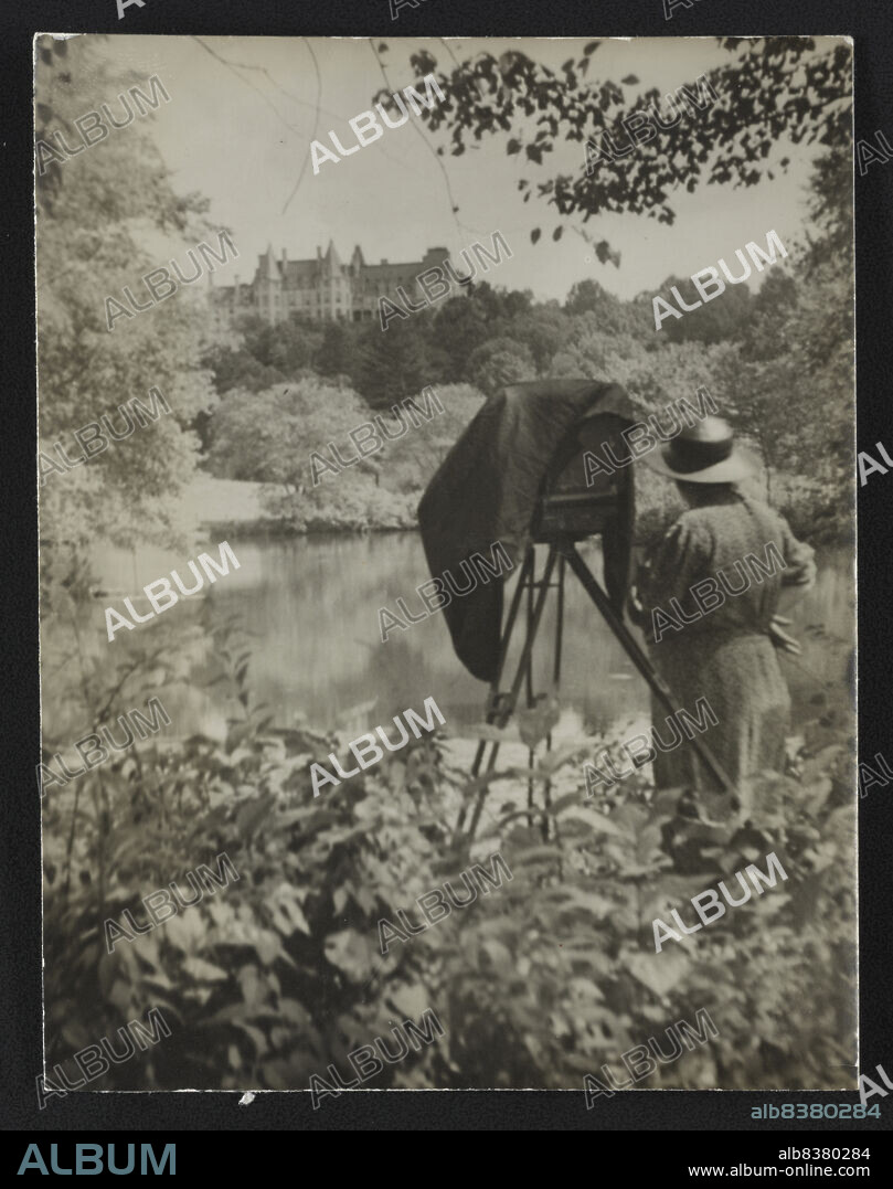 Photographer Frances Benjamin Johnston standing beside her large view camera looking towards the Biltmore Estate mansion in the background, c1938.