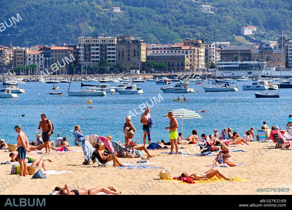 Bañistas en la Playa de Ondarreta, detrás el Casco antiguo o Parte Vieja de la ciudad, Donostia, San Sebastian, Ciudad cosmopolita de 187.000 habitantes, destaca por su gastronomía, playas urbanas y edificios inspirados en la arquitectura parisina, Gipuzkoa, Basque Country, Spain, Europe.