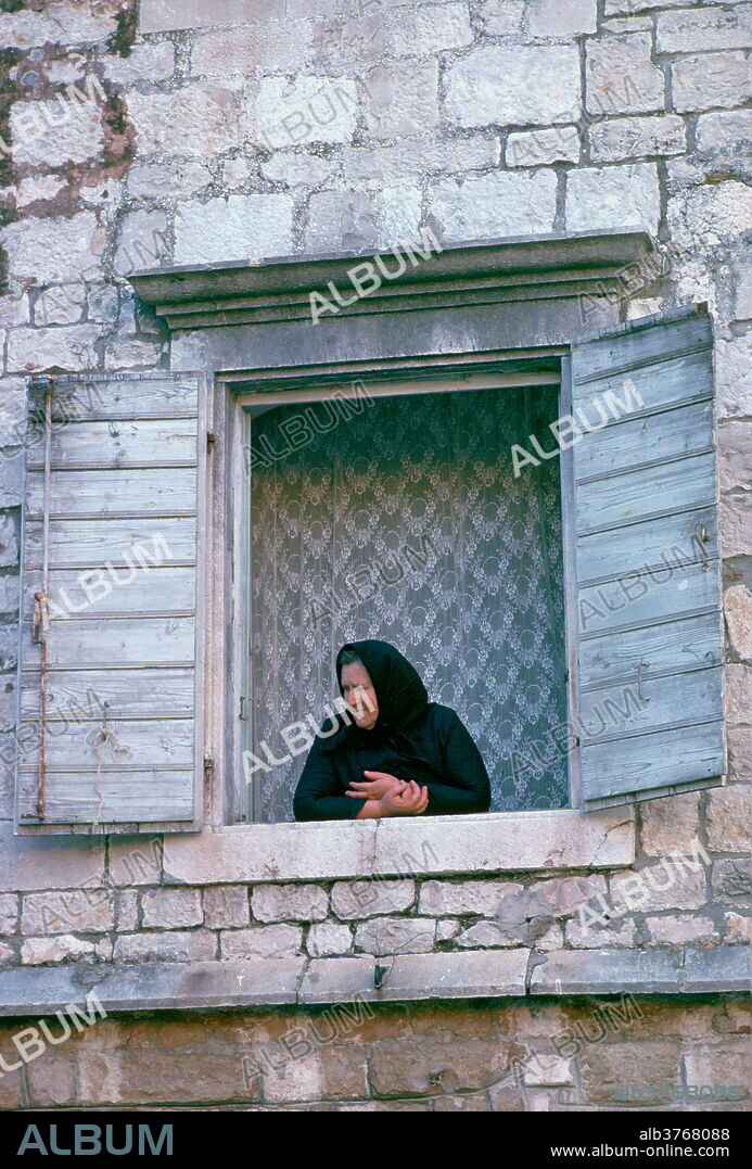 A woman watching from her window in Kotor, Montenegro, - formerly Yugoslavia - a UNESCO World Heritage Site.