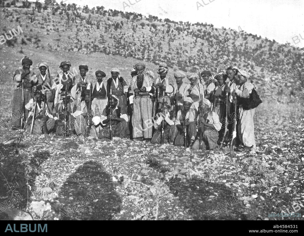 'Ahmed Agha', c1906-1913, (1915). Kurdish men with rifles and bullet belts, Shirwan, (eastern Turkey). 'A little further on we met Ahmed Agha and fifty gunmen. The Agha was a tall, handsome old man, with a pathetic and harassed expression. He pointed sadly to the smoking ruins beyond the river, and showed us the wretched burnt-out inhabitants, collecting wood and stones with which to build fresh houses...When I saw this devastation, I began to think of the advantages of centralised government over feudal times'. From "The Caliphs' Last Heritage, a short history of the Turkish Empire" by Lt.-Col. Sir Mark Sykes. [Macmillan & Co, London, 1915].