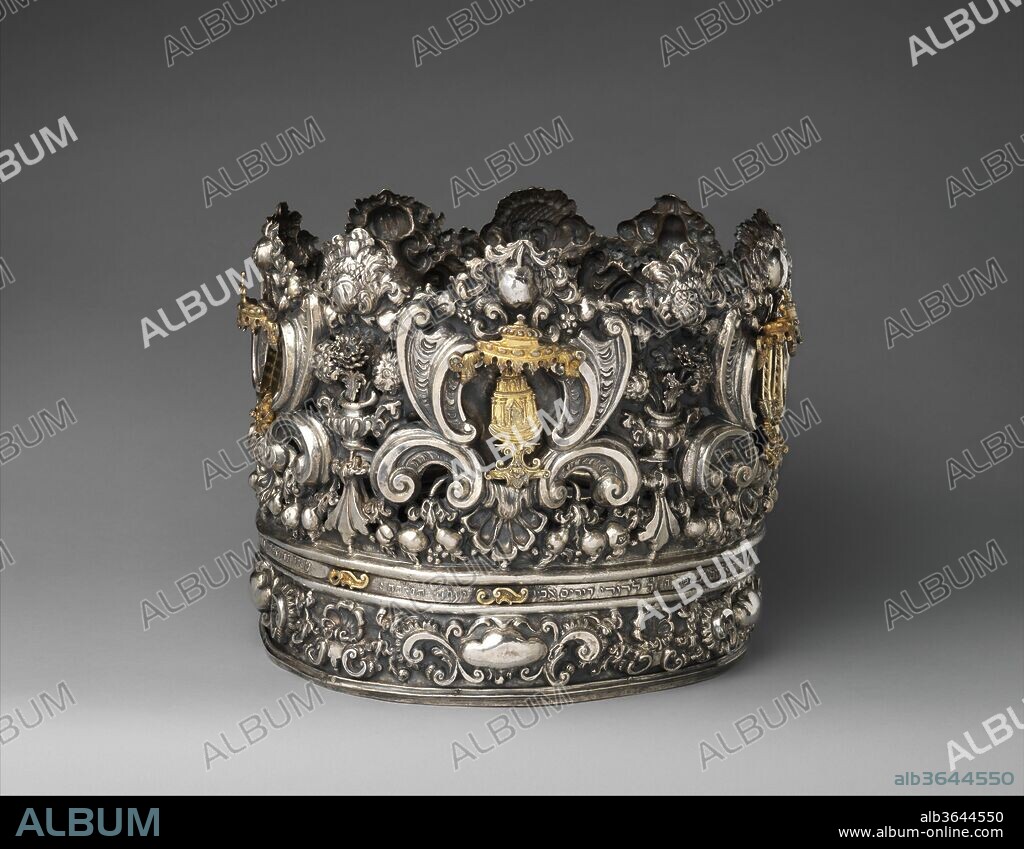 Torah crown (keter). Culture: Italian, Venice. Dimensions: Overall (confirmed, irregular diameter): 10 13/16 × 12 3/8 × 12 3/8 in. (27.5 × 31.4 × 31.4 cm). Silversmith: Andrea Zambelli "L'Honnesta" (Italian, active 1732-1772). Date: ca. 1740-50.
Exceptional for its size and precious material, this Torah crown is a rare survival of 18th-century Italian silver and a testimony to the artistic virtuosity of goldsmithing in Venice. In synagogues the scroll of the Torah, the first five books of the Hebrew Bible, is often decorated with a set of vestments and silver ornaments including a crown or finials, and a shield. The crown augments the Torah's status as an object associated with royalty and speaks to the centrality of the Torah in Jewish life. The motifs depicted include ritual references such as priestly garments, a miniature temple, a menorah, and the Tablets of the Law, the latter engraved in Hebrew with the Ten Commandments. Such rich embellishment is indicative of the wealth and influential status of the Jewish congregation in the Venetian city state. The maker, Andrea Zambelli, is known to have made a wide range of ritual Judaica as well as religious silver for the local churches. A later inscription in Hebrew documents that this "crown of glory, and diadem of beauty" [Isaiah 28:5], was given by the philanthropist and president of the Jewish community in Padua, Gabriel Trieste, to his congregation in the mid-19th century.