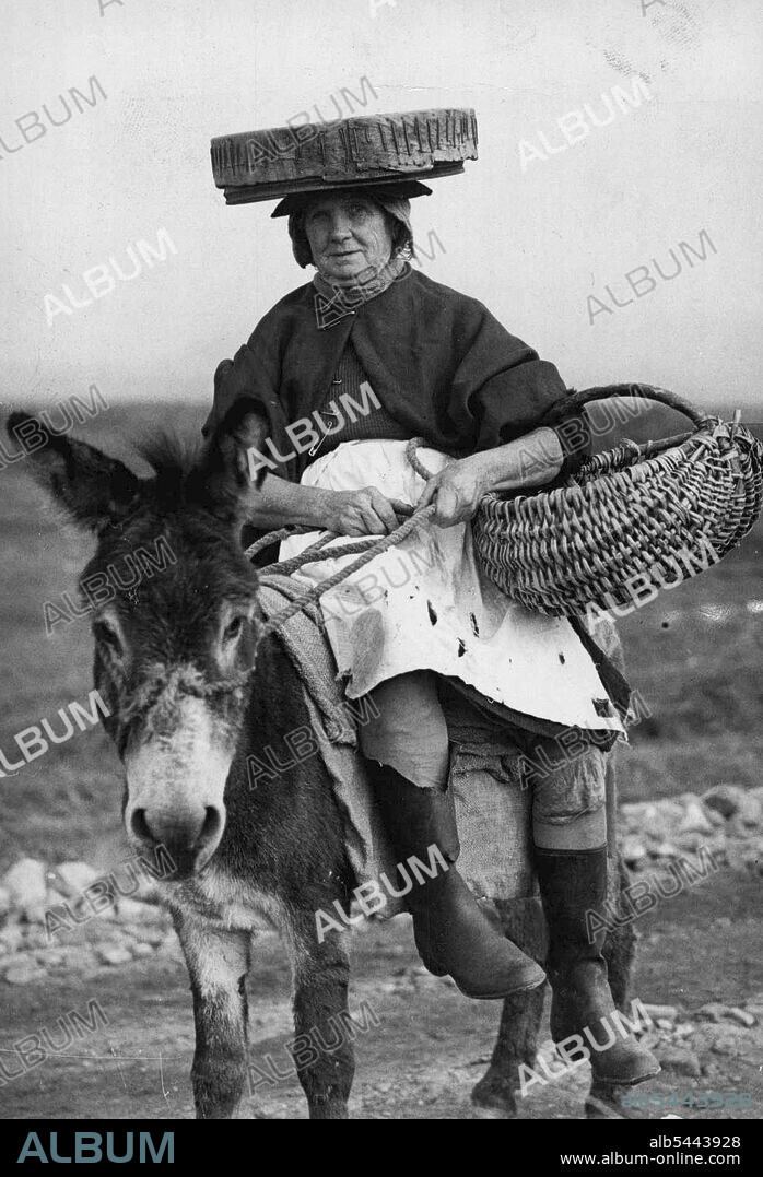 The "Cookle Women Of Penclawdd" -- A typical cockle women is Mrs. Annie Rynon, and as the tide goes out so does Mrs. Eynon on her donkey, complete with the sieve which is the chief implement of her trade. The block Atlantic winds which sweep the desolate sands of Llanrhidian do not daunt her nor the possibilities of "unexploded shells and bombs about which large notices warn her. Women wearing sieves on their heads and riding tiny donkeys and pony-carts make their living by searching for cockles left by the ebbing tide, Llanrhidian Sands, South Wales is Britain's biggest cockle centre, and the families who work the cockle beds have done so for generations. One of the cockle women of Penclawdd, Mrs. Annie Eynon. She collec's cockles on the Llaurhidrau Sands. October 23, 1947.