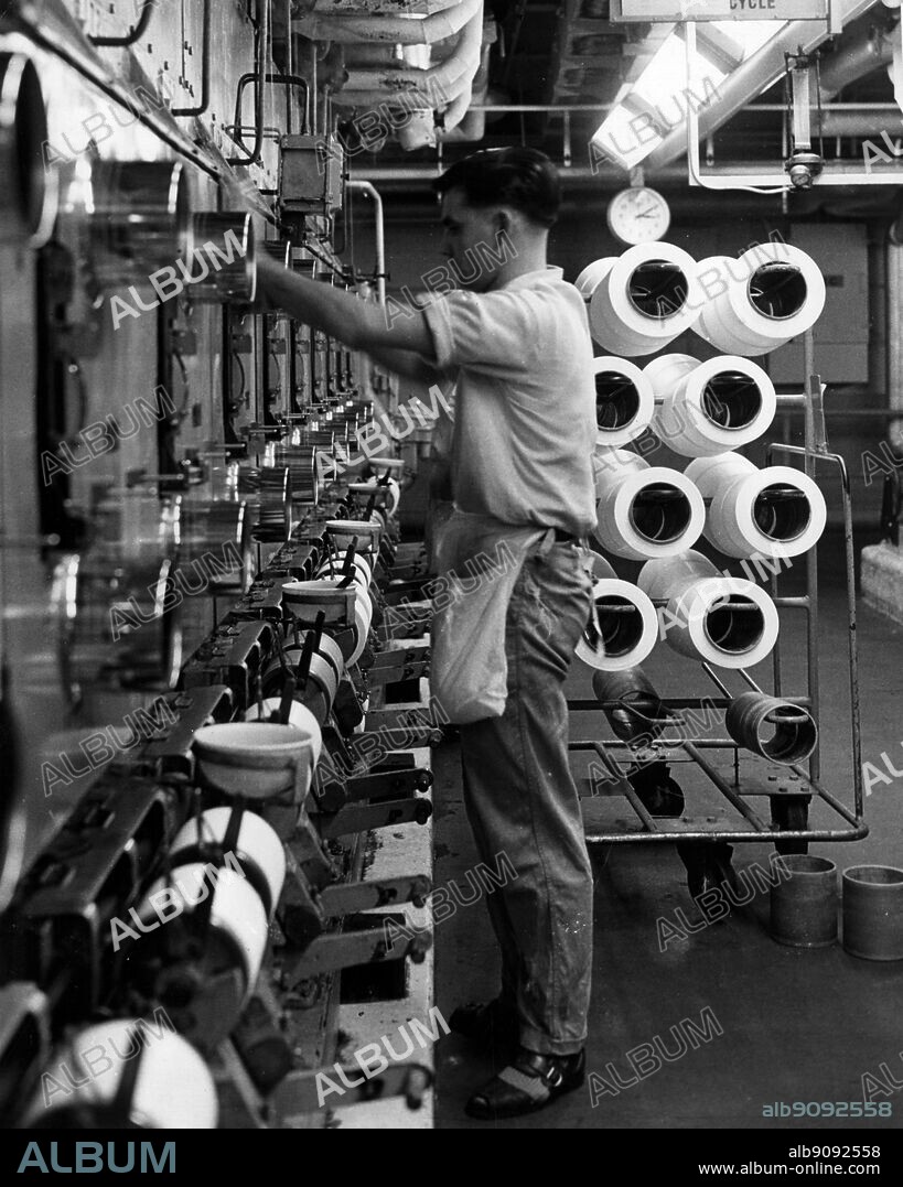First stage in the production of nylon yarn involves melting the polymer and extruding it through spinnerets. Currents of air cool and solidify the extruded polymer which is then wound onto cylinders ready for cold drawing and subsequent processing. Here some of the spinning units in the main plant at the BNS headquarters at Pontypool Monmouthshire. British Nylon Spinners Ltd.