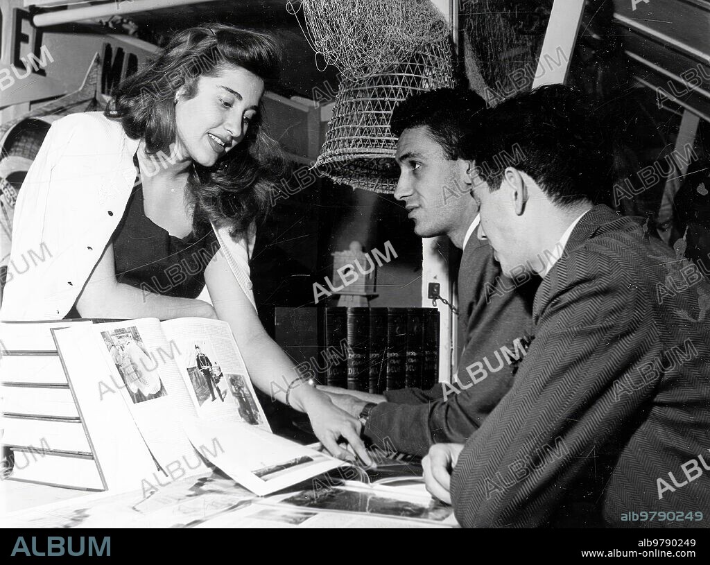 Madrid. 1957 (CA.) Una mujer enseña libros a dos hombres interesados.