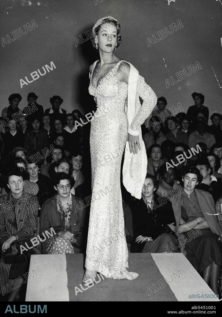 Students Of Fashion -- A Norman Hartnell whit lace evening dress, embroidered with beads and sequins, is modelled for students in the style and Beauty fashion show at the Barrett Street Technical College, Oxford Street, London, to-day (Monday).The show aims to demonstrate that smartness does necessarily depend on high price but can be achieved by blending make-up, accessories, and good basic fashions.When she models a Hartnell evening gown to show that smartness doesn't necessarily mean high price, she still looks like a million dollars. October 20, 1952. (Photo by Reuterphoto).