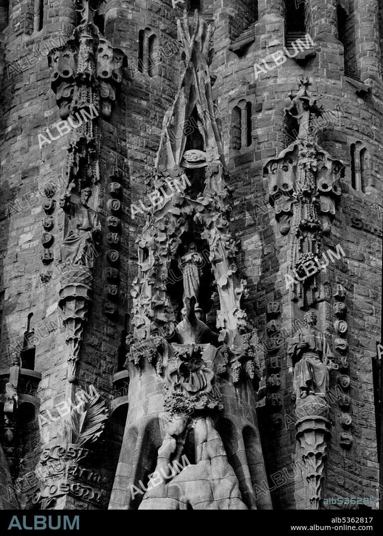 JOAN MATAMALA FLOTATS. Sagrada Familia (Nativity Facade): portico of the Faith with the Immaculate Conception that is inside a crucible of three pipes that represent the Holy Trinity and on the summit there is the hand with the eye that sees everything as a symbol of Divine Providence, 1934.