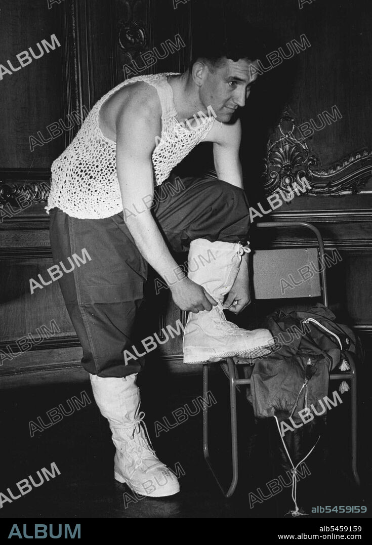 Dressing for the Artic - Fur-lined boots are adjusted by Lieut. F. R. Brooke, R.N. He has already donned a string vest. Boots and vest are part of the Artic clothing he will wear as a member of next month's Combined Services expedition to North Greenland. June 18, 1952. (Photo by Daily Mail Contract Picture).