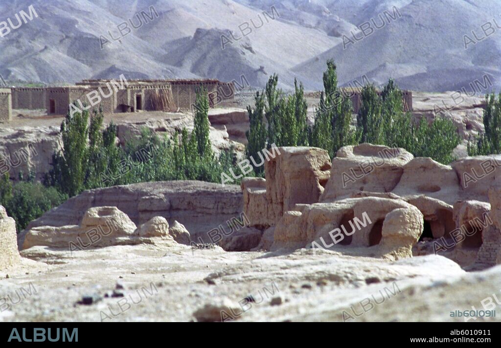 CHINA Xinjiang Turpan View over the Ancient ruins in desert landscape toward distant buildings.
