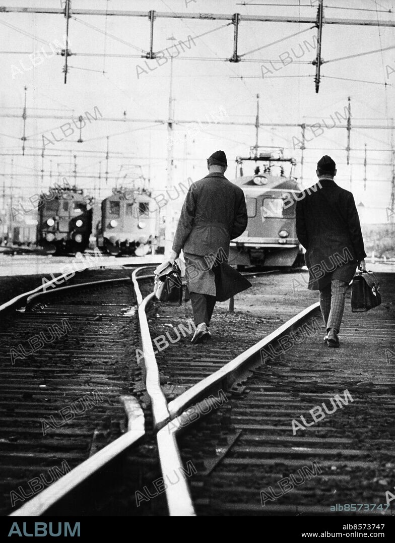 Lokförare går på sitt pass. Med väska och kläder mellan tåg på Malmö C 1989. Lokförarna i arbete efter SACO-SR-konflikten 1971.. Foto: Lennart Peters / Sydsvenskan / IBL Bildbyrå *** Local Caption *** Engine drivers on their way to the engine, Malmoe Central Station, Sweden, 1971.