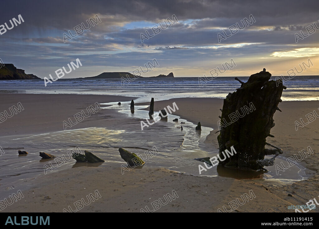 Sunset over the wreck of the Helvetia and Worms Head at Rhossili Bay, Gower, Wales, United Kingdom, Europe.