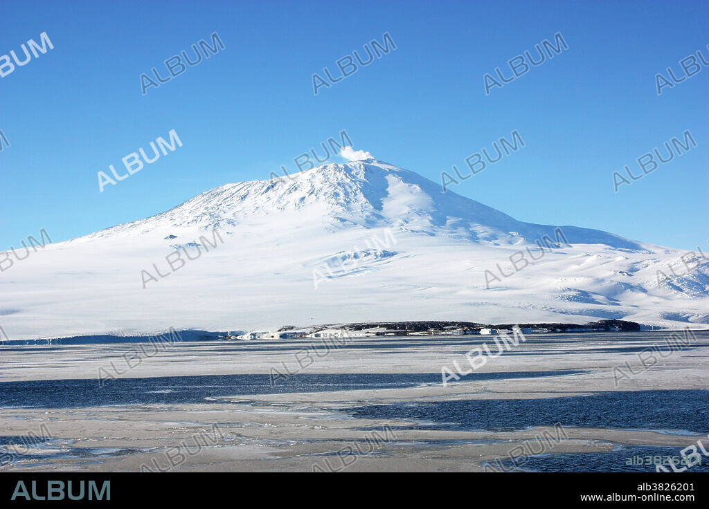Mount Erebus Volcano, Antarctica. February 22, 2009. Antarctica inside the Antarctic Circle taken from McMurdo Ice Shelf looking towards Mt. Erebus. Mount Erebus Volcano, at 12,280 ft (3,743 m) high, is one of Earth's loftiest active volcanoes. It was discovered in 1841 by the British explorer James C. Ross. With 98% of its surface covered with ice it is hard to remember there is a rock underneath all of those tons of frozen ancient water. Mount Erebus erupts about ten times per year and even though it is encased in thick ice a molten red lava lake lies inside its summit crater. Its sides are layered with both glacial ice and old lava flows like a layercake. Strange ice formations are built over fumaroles towering some 1,000 feet tall. Erebus is strange in that its bottom half is a shield volcano and its top half a stratovolcano.